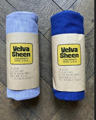 Zwei gerollte Velva-Sheen-T-Shirts in Papierbanderolen